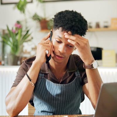 A business owner appearing to be frustrated while on a call because of loan application woes.