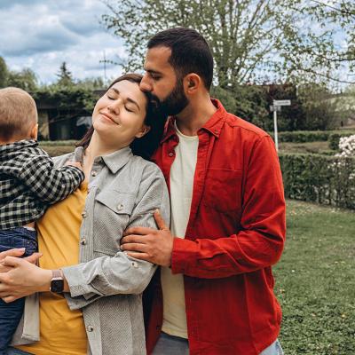 A young family of 3 spending time together outdoors in a park.