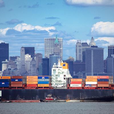 A large container ship carrying imported products entering a port in New York.