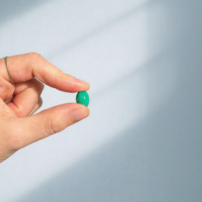 Hand holding a small pill against the sunlight