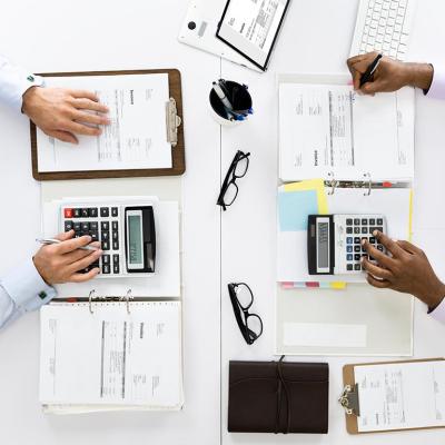 An overhead shot of a tax accountant and an auditor checking on receipts in an office.