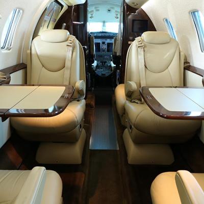 A private business jet cabin with open tables on both sides and lowered armrests.