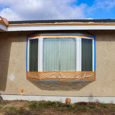 A portion of a house for sale covered with protective plastic for a repainting job.