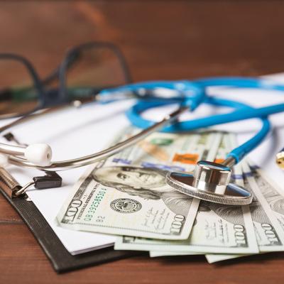 U.S. dollar bills, medical records, and a stethoscope placed in a desk.