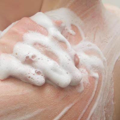 Person exfoliating shoulders with body wash during a shower.