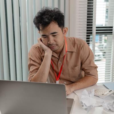 A male employee looking tired at work reviewing reports.