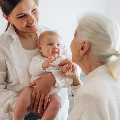 A grandmother looking at her adult daughter and newborn granddaughter.