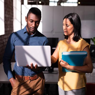 Two colleagues standing in an office discussing a task together.