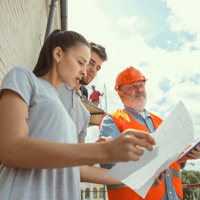 A foreman showing a young couple the plans to their new home.