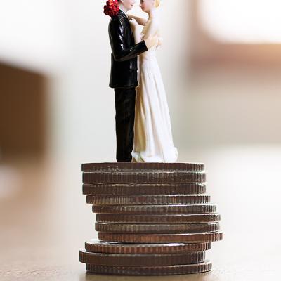 Figure of a married couple on top of a stack of coins as a concept of saving for a wedding.