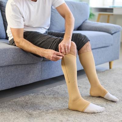 A man putting on knee-high compression stockings at home.