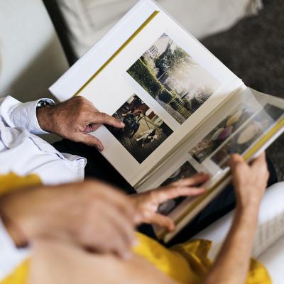 An elderly couple browsing and looking through a photo album.