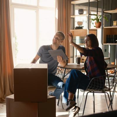 A couple surrounded with packed boxes discussing room organization after moving in.