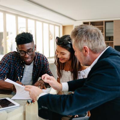 A young couple signing a property contract with a real estate professional.
