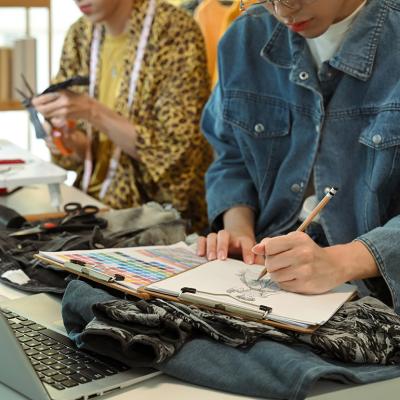 Fashion designers sketching and crafting new clothing designs in their studio.