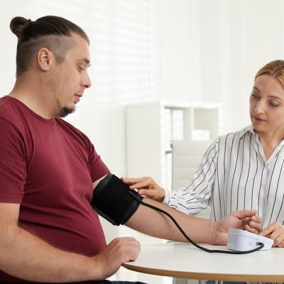 A nutritionist measuring a patient's blood pressure using a manual sphygmomanometer in a clinic. 