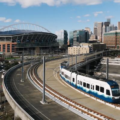 A Sound Transit Link light rail train, with the Lumen field and Seattle skyline in Washington, USA.