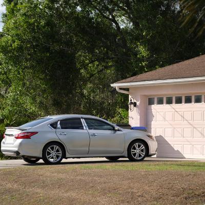 A car parked in front of a modern American house's garage. 