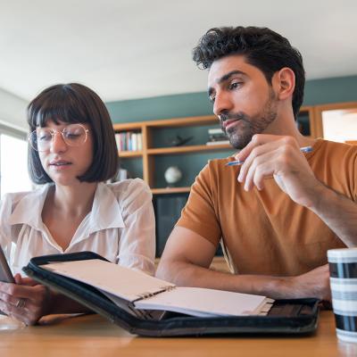A young couple reviews and pays bills online using a digital tablet.