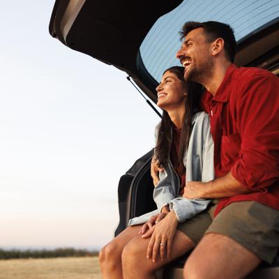 A couple taking a break at their car's trunk from a long drive trip.
