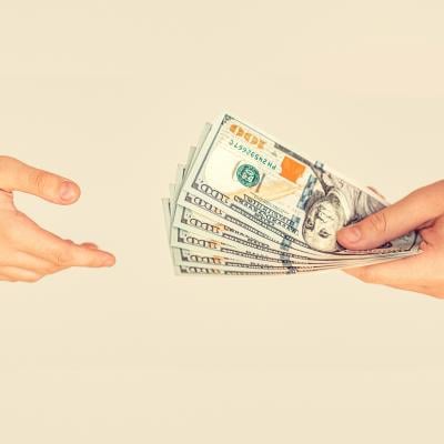 A financial transaction where one person is handing US banknotes to another person.