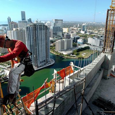 A construction worker makes his way up the side of a condominium highrise construction site in downtown Miami, Florida.
