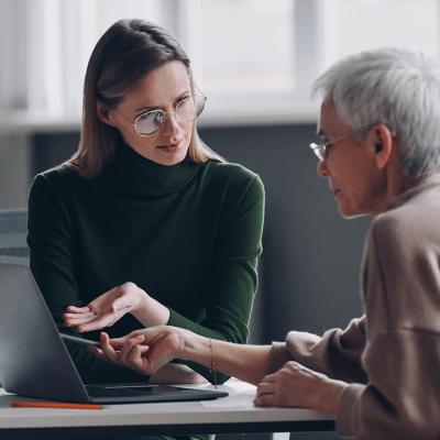 A financial advisor discussing plan options for a life insurance with an elderly client in the office.
