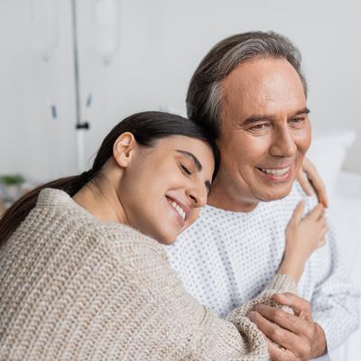 A daughter hugging her father, who is recovering from an illness in the hospital.