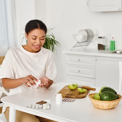 A nutritionist taking food supplements alongside eating fresh fruits at home.