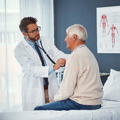 A doctor assessing an elderly person's breathing with a stethoscope during a medical check-up.