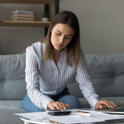 A focused woman at home reviewing financial reports.