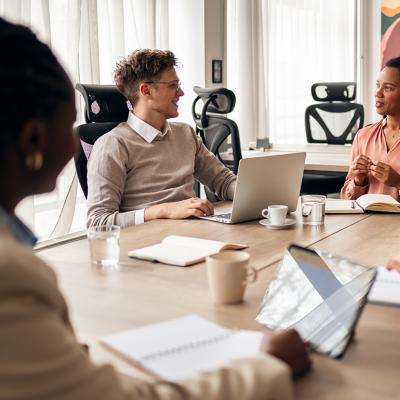 A diverse group of business professionals engaged in a discussion in a meeting room.