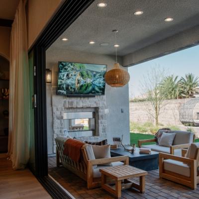 A modern covered patio in a backyard with extended living area, outdoor television, and fireplace. 