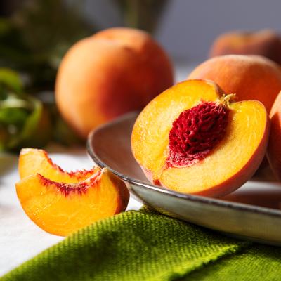 A freshly cut yellow peach with a red pit.