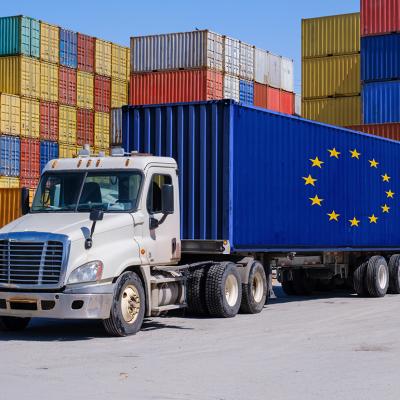 A truck in a shipyard with an EU-marked shipping container.