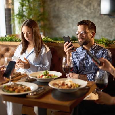 A group of business colleagues checking their smartphones while eating lunch in a restaurant.