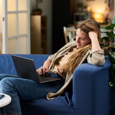 A stressed young woman at home looking at taxes from a laptop.