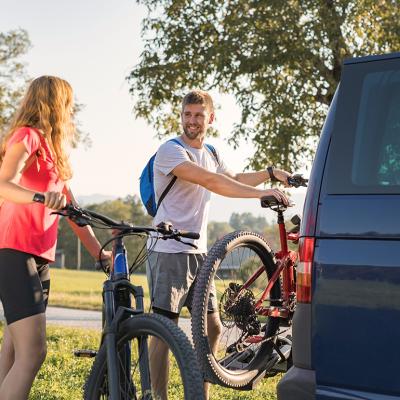 A couple taking down electric mountain bikes from their van for a nature recreational adventure.