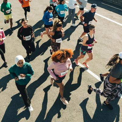 Aerial view of a diverse group of participants running in an organized outdoor race. 