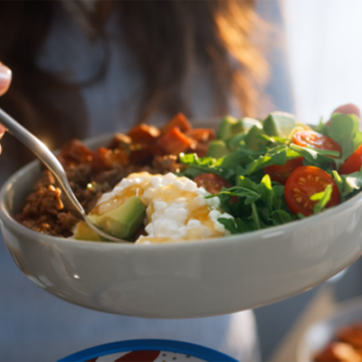 A woman holding a bowl of salad with cottage cheese.