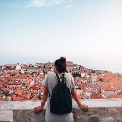 A young tourist looking over red-brownish roofs from Old Town in Dubrovnik, Croatia.