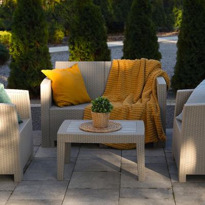 An outdoor rattan garden furniture set with yellow and cream motifs.
