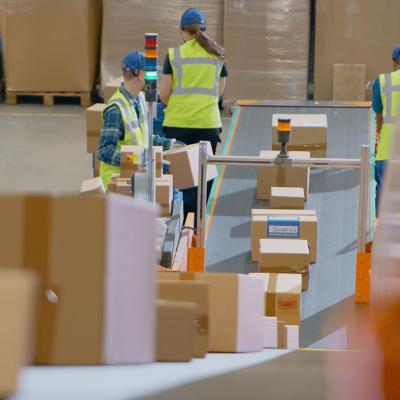 A logistics team in a warehouse working along a conveyor belt to sort and load packages.