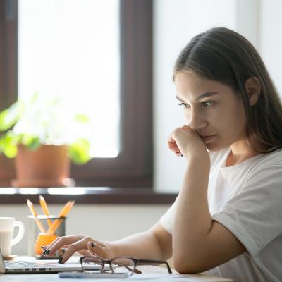 A person appearing to be suspicious while reading from a misleading online content from a laptop.
