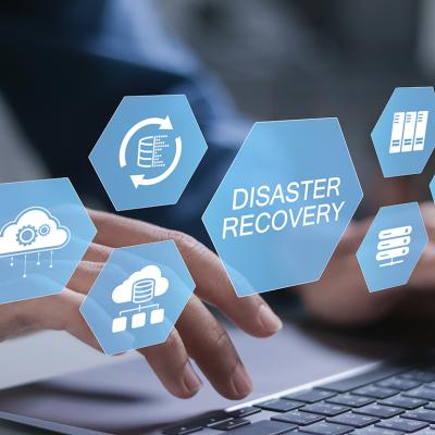 Businessman typing over a keyboard illustrated with conceptual graphics for a cyber disaster recovery system.
