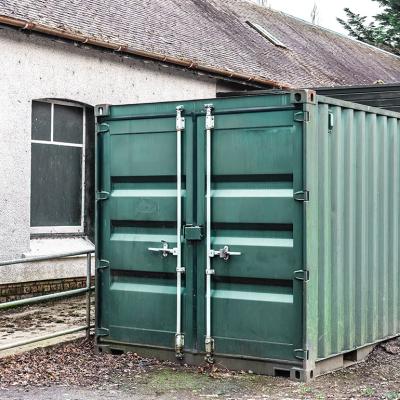 A large steel storage container positioned outdoors beside a building.