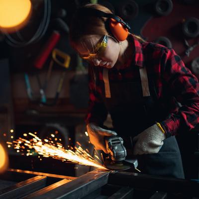 A tradeswoman working with an angle grinder.