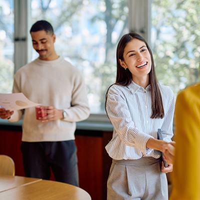 A businesswoman enthusiastically shaking hands with a new coworker.