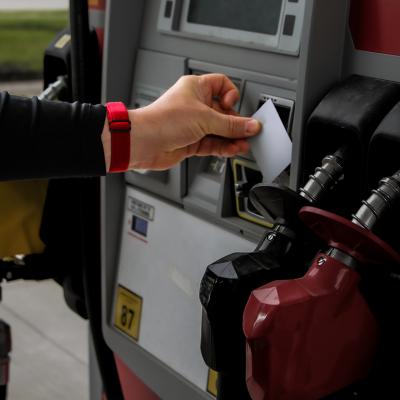 Person tapping credit card onto a gas station payment reader.