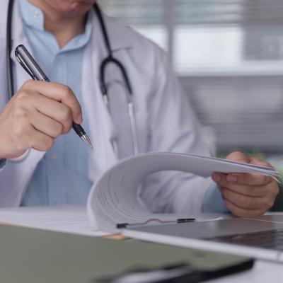 Doctor hand writing medical report on clipboard.